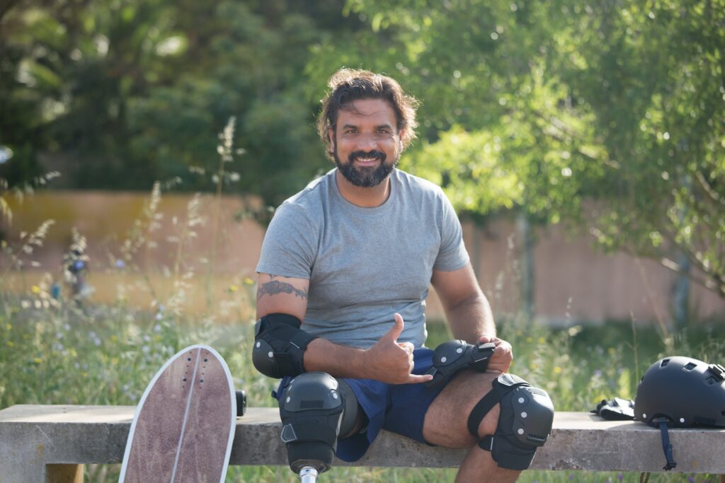 Man Wearing Elbow and Knee Pads Sitting on Concrete Bench